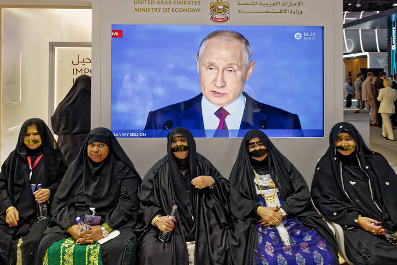 Иностранные участники форума на фоне трансляции выступления президента России Владимира Путина на пленарном заседании
