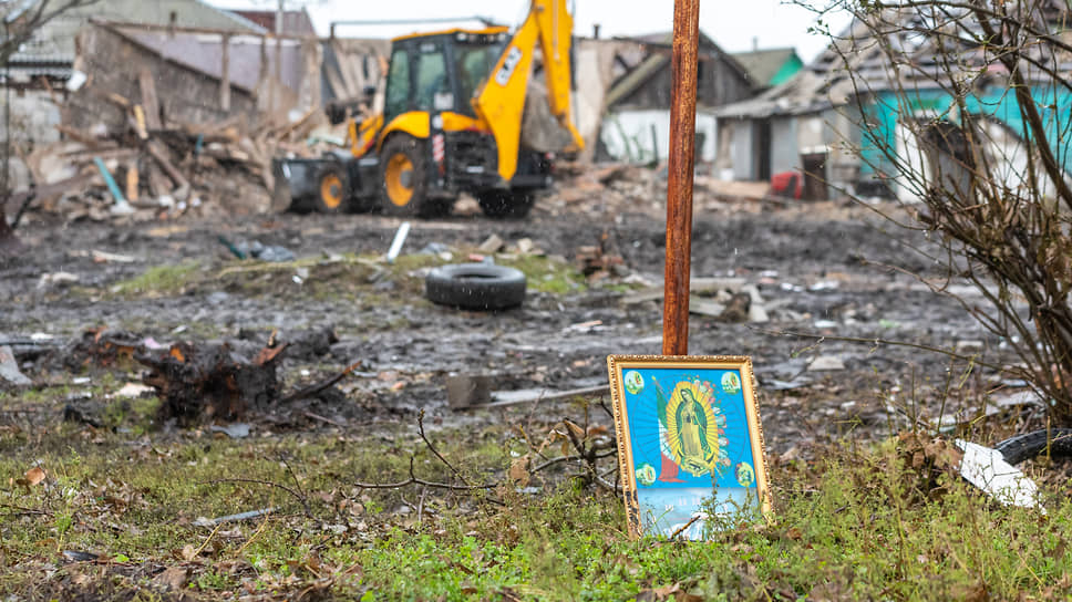 Часы с иконой у опоры газовой трубы на площадке у разрушенных домов