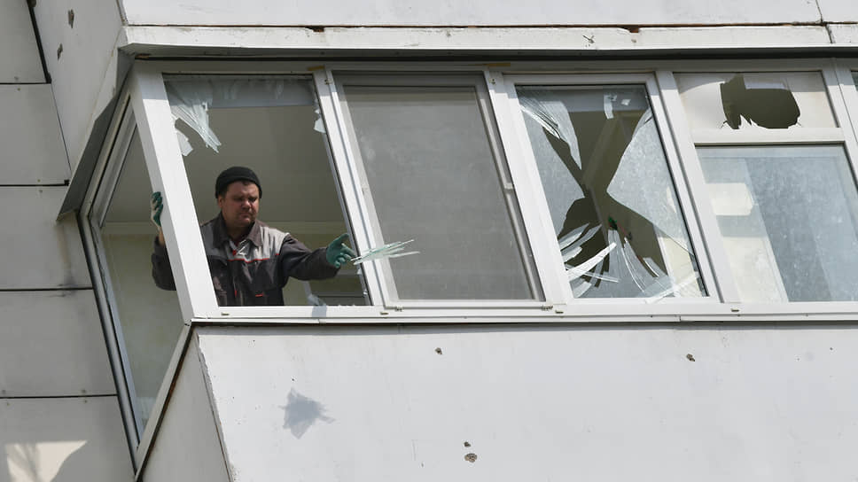 Рабочие очищают оконные рамы от фрагментов стекол на улице Есенина