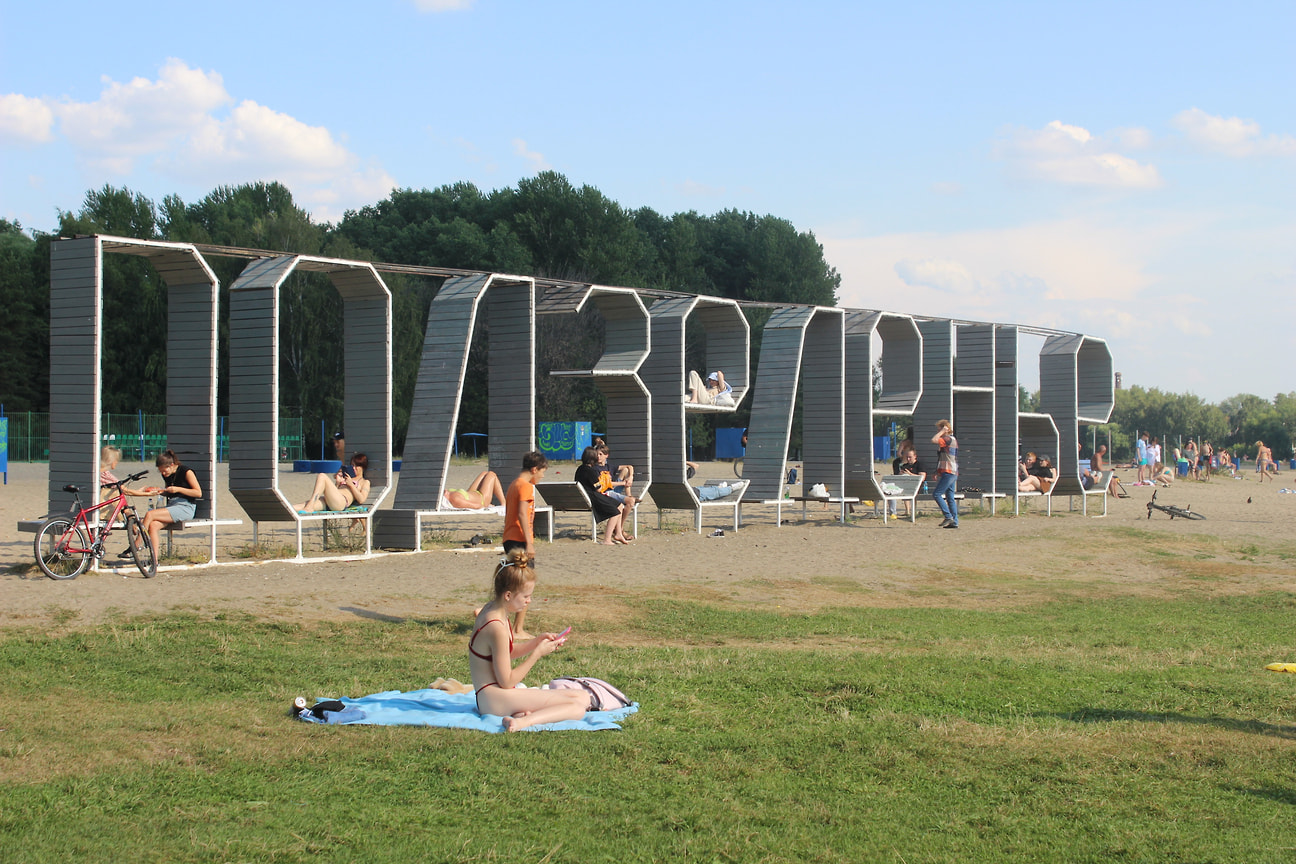 Люди в центре Ярославля на берегу реки Которосль на пляже Подзеленье прячутся от зноя в тени огромных букв с названием локации