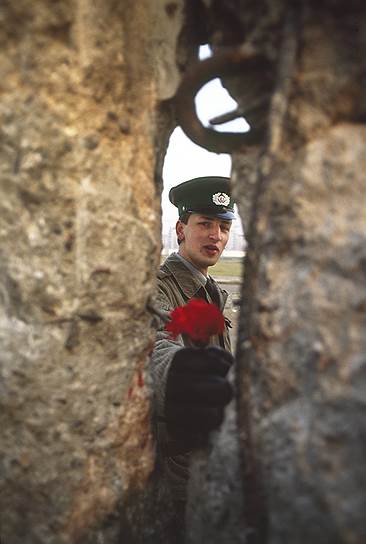 Солдат армии ГДР протягивает цветок через стену, 10 ноября 1989 года 
