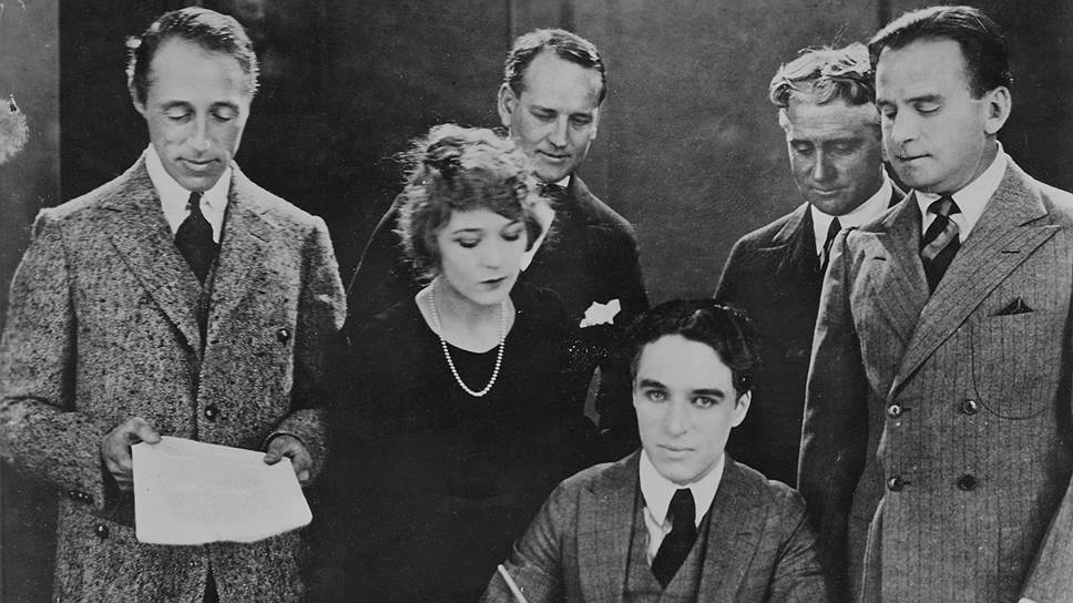 Звезды немого кино подписывают документы о создании компании United Artists. В первом ряду слева направо: Д. У. Гриффит, М. Пикфорд, Ч. Чаплин, Д. Фэрбенкс