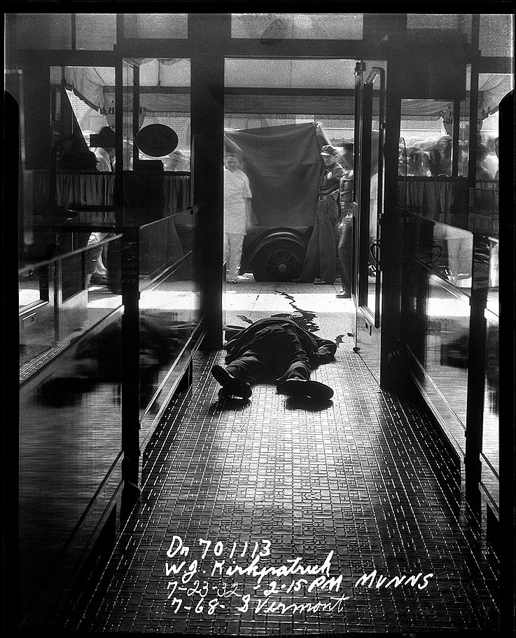 Вермонт-стрит, 768. Мертвое тело в выложенном плиткой коридоре, на заднем плане полицейские поднимают простыню. 1932 год. Фотограф: Маннз 

