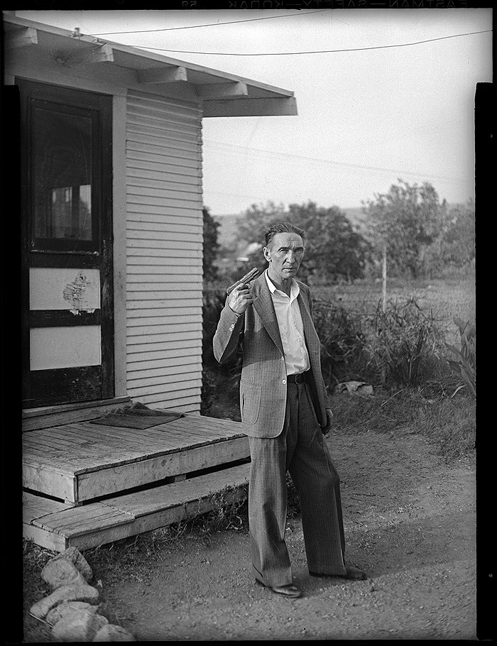 Мужчина, стоящий у черного входа в дом и целящийся в себя из пистолета. 1942 год