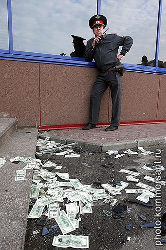 СПАСТИ РЯДОВОГО ФРАНКЛИНА&lt;br>Сотрудник милиции и стодолларовые купюры, разбросанные на асфальте после штурма офиса сети гипермаркетов «Лента». Санкт-Петербург, 2010 год