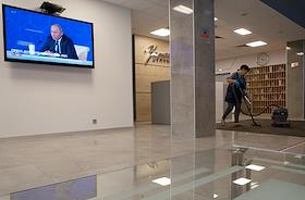 Broadcast of the press conference of Russian President Vladimir Putin on the Dozhd TV channel in the lobby of the business center during cleaning.