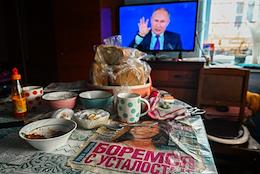 Genre photographs. Retirees watch the Big Annual Press Conference of Russian President Vladimir Putin on TV at home.