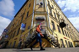 A public utility employee paints over a portrait of the poet Daniil Kharms on the facade of a house on the corner of Kovnosky Lane and Mayakovskaya Street.